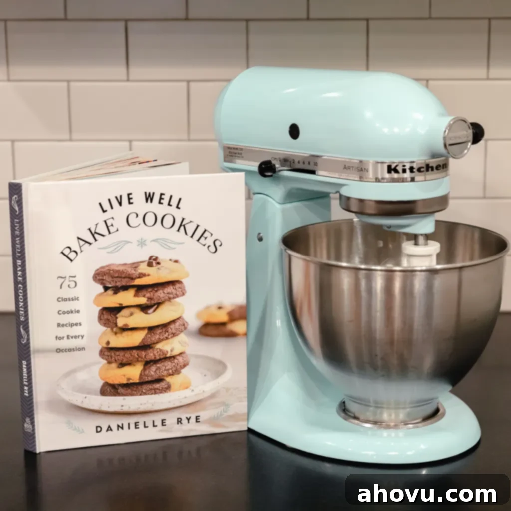Holiday Baking Stand Mixer Giveaway 2 A cookbook sitting next to a blue KitchenAid stand mixer on a black countertop, symbolizing a joyful baking experience.