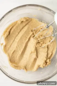 An overhead view of cookie dough in a glass mixing bowl.