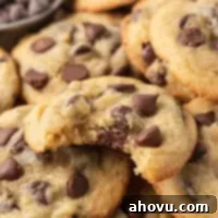 Several chocolate chip pudding cookies stacked on top of each other. The top cookie has a bite missing.