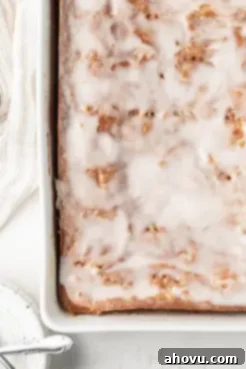 An overhead view of an iced honey bun cake in a white baking dish.