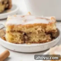 Glazed Cinnamon Honey Bun Cake 8 A slice of honey bun cake on a white speckled plate.