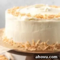 Tropical Coconut Dream Cake 7 A coconut cake decorated with toasted coconut on a wooden cake stand.