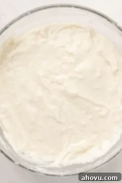 A glass mixing bowl with coconut cake batter in it.