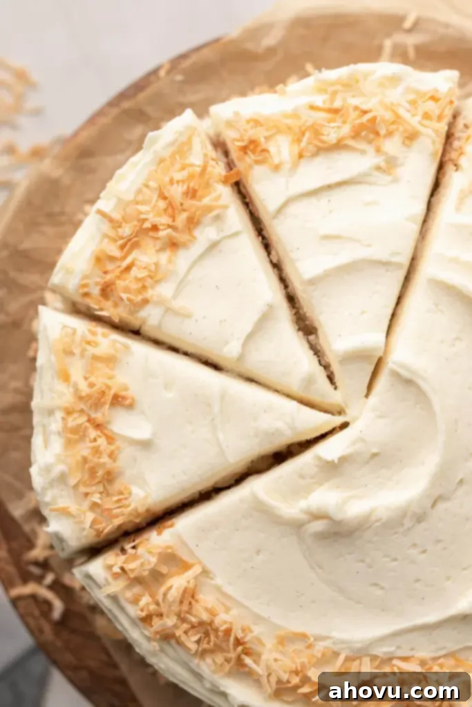 Tropical Coconut Dream Cake 4 An overhead view of a frosted coconut layer cake on a cake stand. Three slices have been cut.