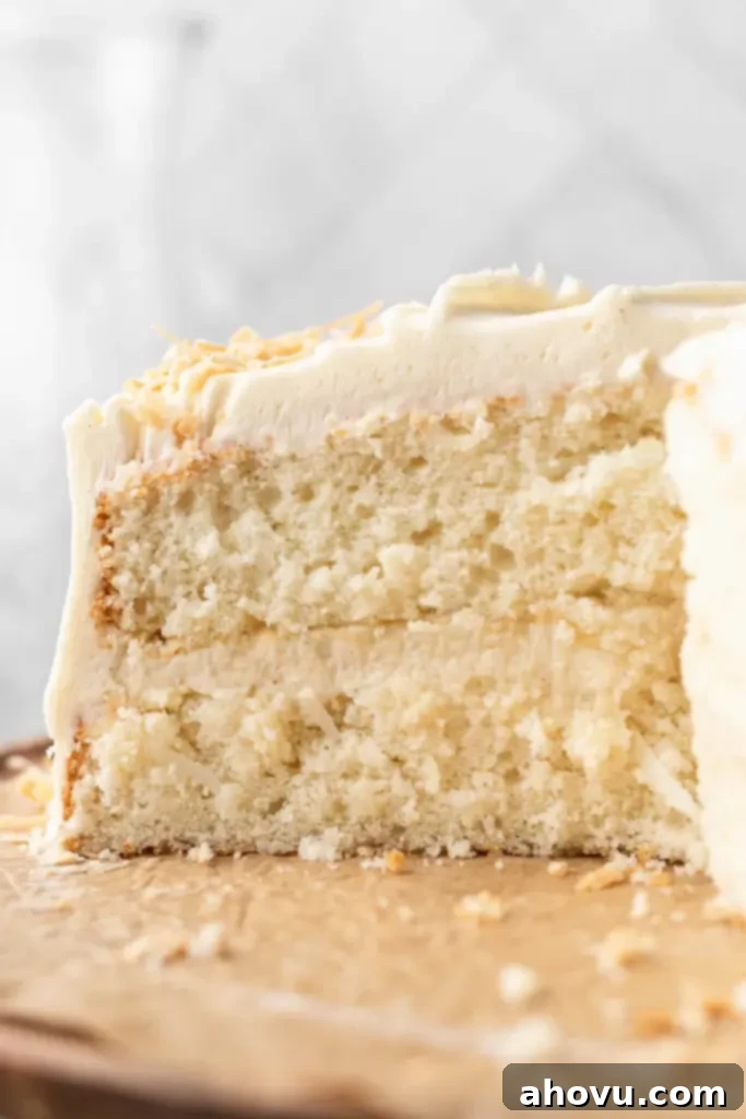 Tropical Coconut Dream Cake 5 A side view of a coconut cake that's been sliced to show the interior.