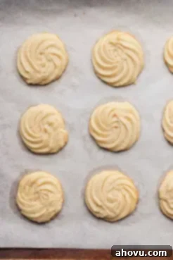 An overhead view of baked butter cookies on a parchment-lined baking sheet.