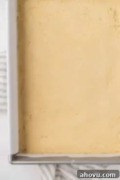 An overhead view of shortbread dough perfectly pressed into a baking pan, creating an even base.