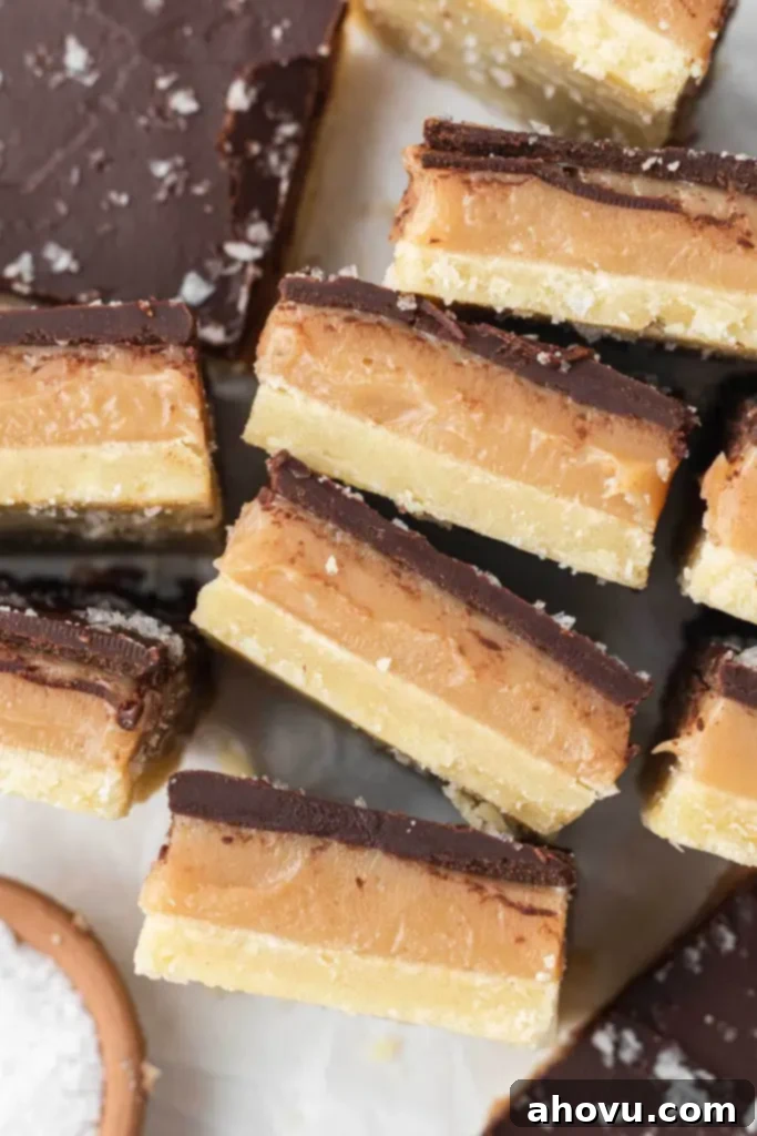 Millionaire Shortbread 4 A close-up, overhead view of perfectly sliced Millionaire Shortbread bars, with some turned on their sides to show off the distinct layers of shortbread, caramel, and chocolate.