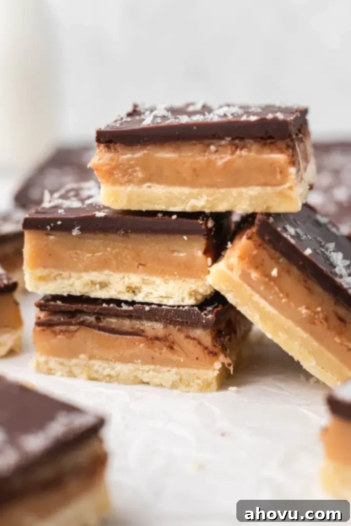 Millionaire Shortbread 6 A perfectly arranged stack of Millionaire Shortbread bars, with another bar leaning against the stack, showcasing their appealing layers.
