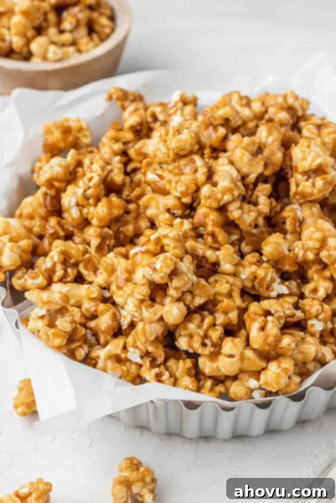 A metal tart pan piled high with homemade caramel corn. A smaller dish of popcorn rests in the background. 
