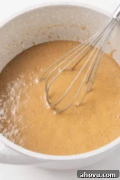 Caramel sauce in a white mixing bowl with a whisk.