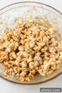 Popcorn coated in caramel sauce in a large glass mixing bowl.