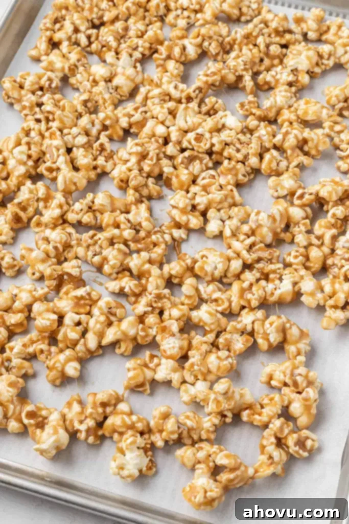 Sticky caramel popcorn on a parchment-lined baking sheet. 
