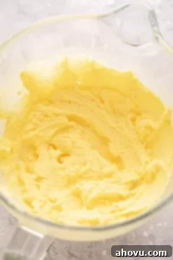 A mixing bowl containing the wet ingredients for the yellow cake, which include egg yolks mixed into the creamed butter and sugar, showing a smooth, emulsified texture.