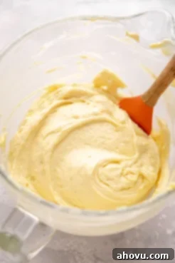 A glass mixing bowl filled with smooth, pale yellow cake batter before the egg whites have been folded in, illustrating a creamy, uniform consistency.