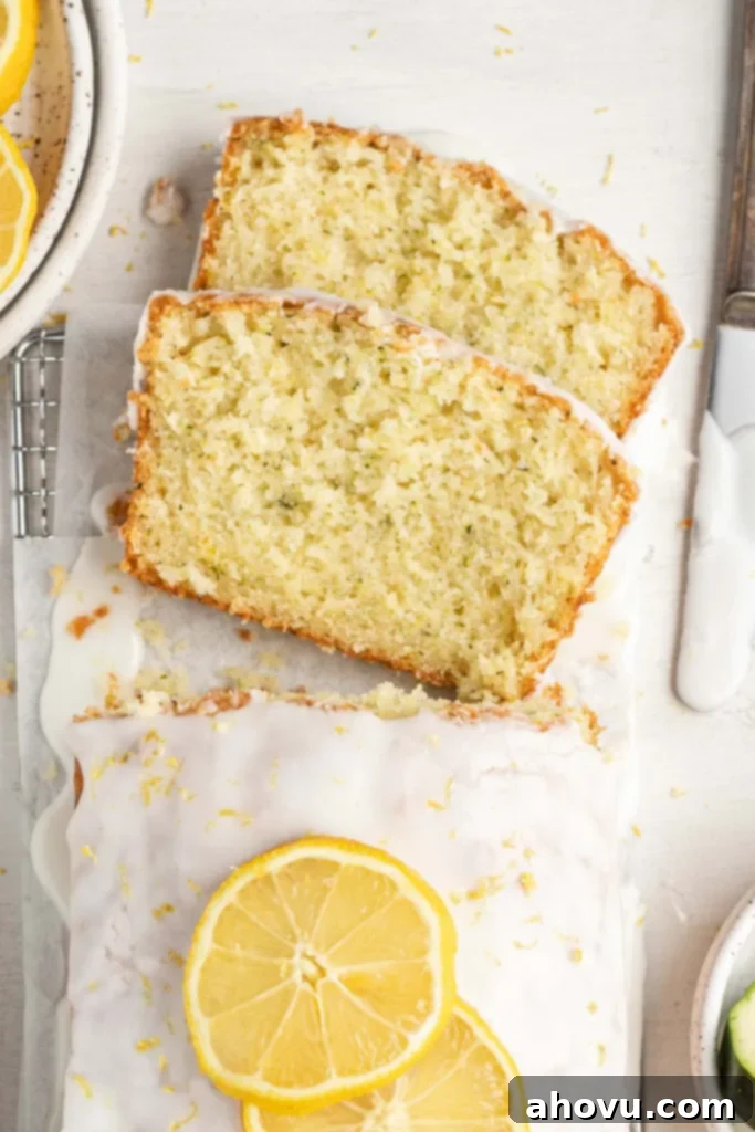 An overhead view of two slices of zucchini lemon bread lying on their sides next to the loaf.