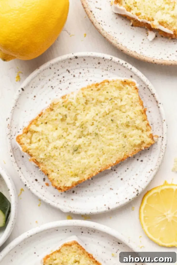 An overhead view of a slice of lemon zucchini bread on a speckled plate. 