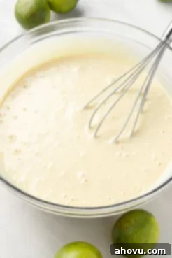 Key lime pie filling in a glass mixing bowl with a whisk.