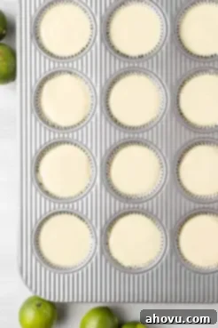 An overhead view of unbaked mini key lime pies in a muffin tin.