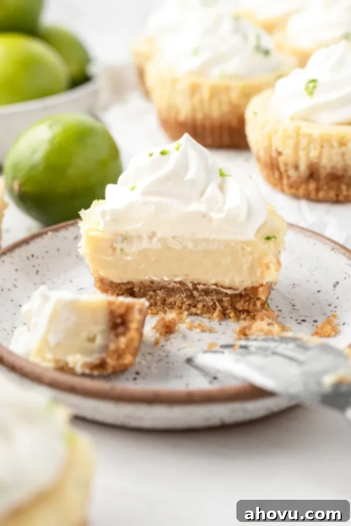 A mini key lime pie on a speckled dessert plate, cut in half to show the layers. 