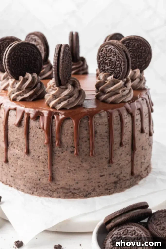 Decadent Oreo Cake 2 A decadent chocolate Oreo cake, beautifully decorated with a glossy chocolate ganache drip, elegant swirls of Oreo buttercream frosting, and whole Oreo cookies adorning the top. The cake is presented on a pristine white cake stand, ready to be served.
