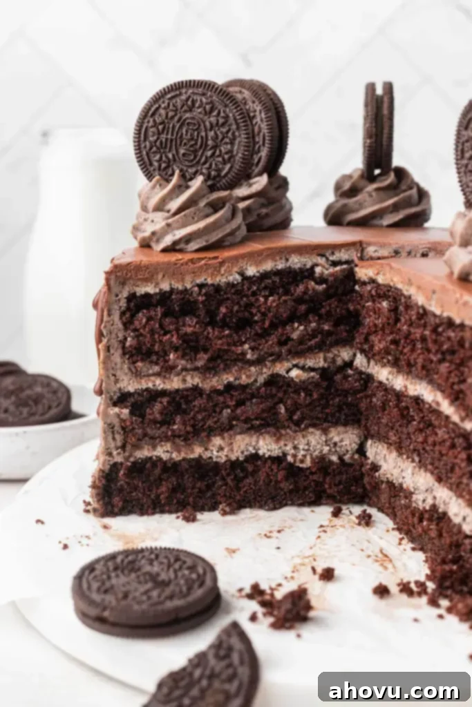 Decadent Oreo Cake 5 A magnificent triple layer Oreo cake, expertly cut to reveal its moist chocolate cake layers interspersed with generous amounts of creamy Oreo buttercream frosting, inviting a delicious tasting experience.