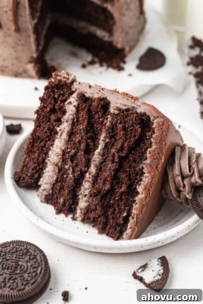 Decadent Oreo Cake 6 A single slice of luxurious chocolate Oreo cake, perfectly positioned on a pristine white dessert plate, with the distinct layers of moist cake and creamy frosting clearly visible, and a delightful bite taken from it.