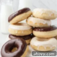 Several baked donuts stacked on top of each other. The donuts are coated in chocolate and vanilla icing, looking irresistible.