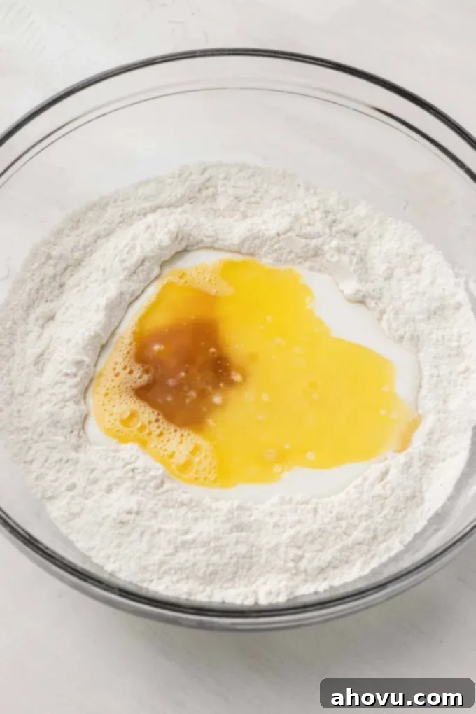 An overhead view showing both the dry and wet ingredients for the baked donut batter combined in a mixing bowl, creating a thick consistency.