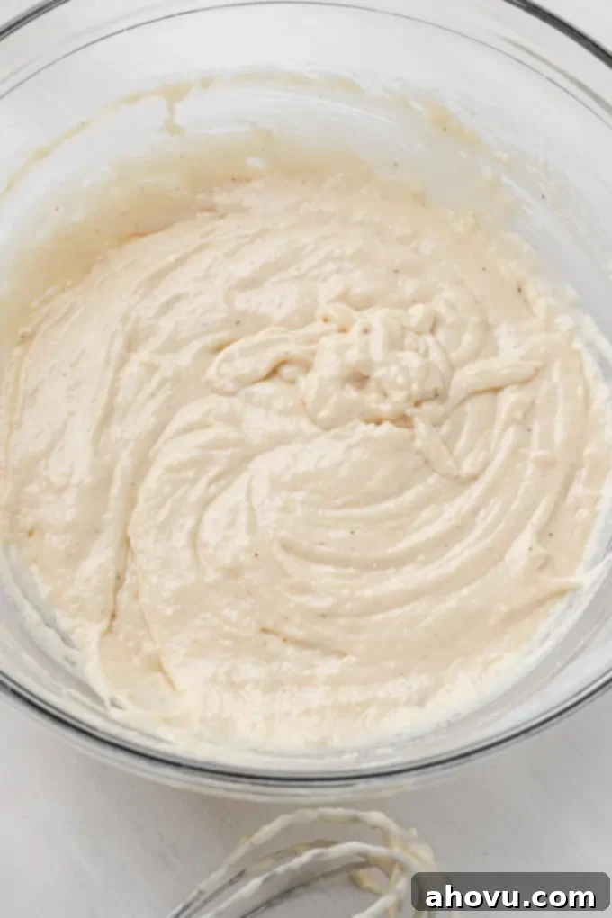 Thick, smooth donut batter resting in a clear glass mixing bowl, ready for piping into the donut pans.