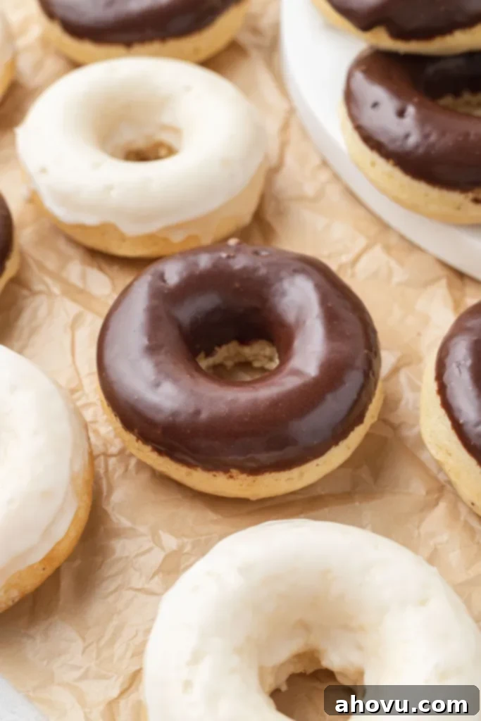 A close-up of beautifully iced baked cake donuts resting on parchment paper, ready to be enjoyed.
