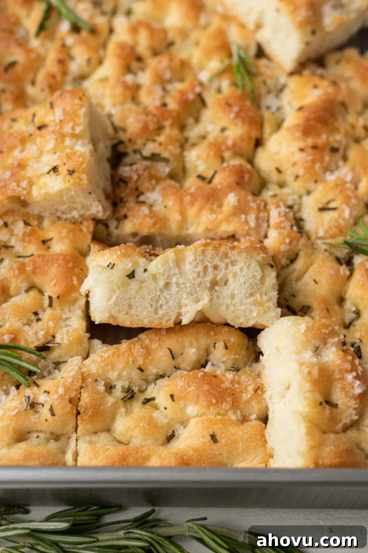 Slices of rosemary focaccia in a metal baking pan. Some slices are turned on their sides. 