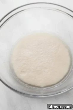 Foamy yeast mixture in a glass mixing bowl.