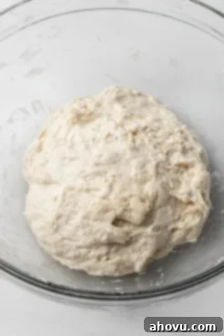 Unkneaded focaccia dough in a glass mixing bowl.