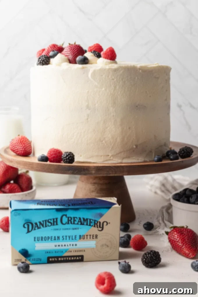 A Chantilly cake on a wooden cake stand, with a package of Danish Creamery butter in front of it. 