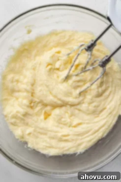 An overhead view of a butter-egg mixture in a glass mixing bowl.