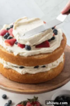 A process shot showing a chantilly berry cake being frosted.