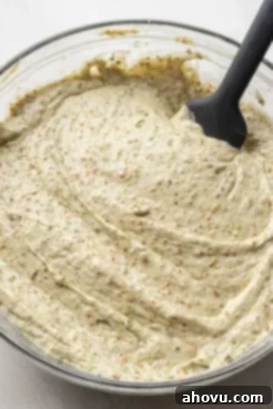 Overhead view of pistachio nut cake batter with a rubber spatula in a glass bowl.