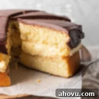 The Original Boston Cream Cake 6 A sliced Boston cream pie on a cake stand. One slice is being removed.