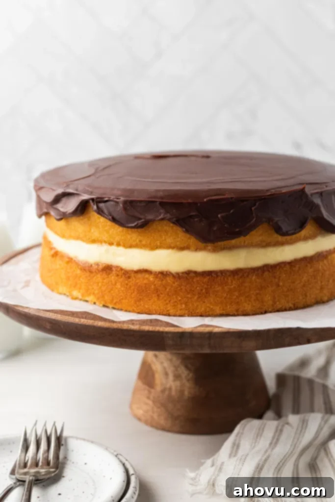 The Original Boston Cream Cake 4 A homemade Boston cream pie on a wooden cake stand.