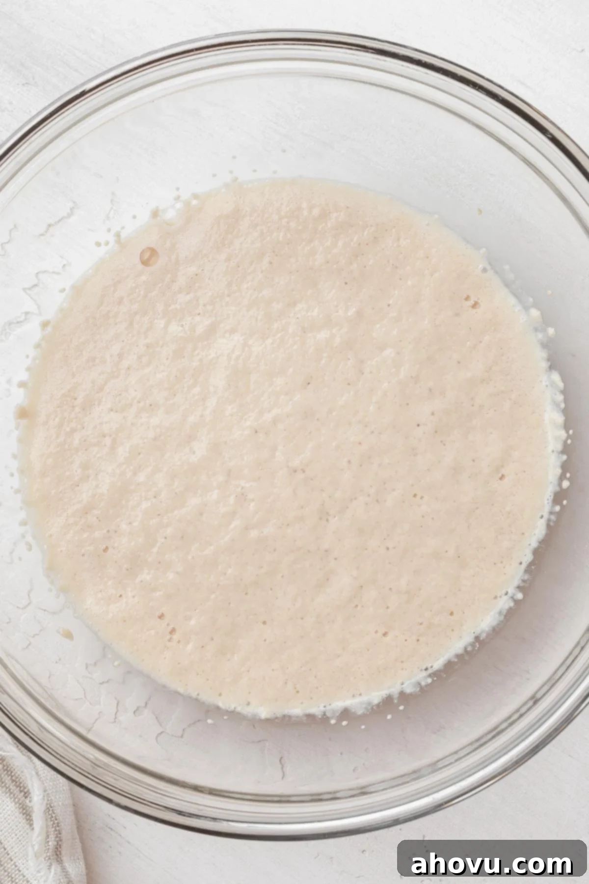 Overhead view of yeast proofing in a glass mixing bowl.