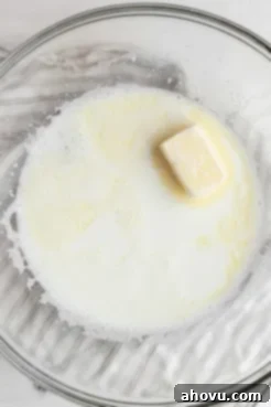 Overhead view of sugar, butter, salt, and scalded milk in a large mixing bowl.