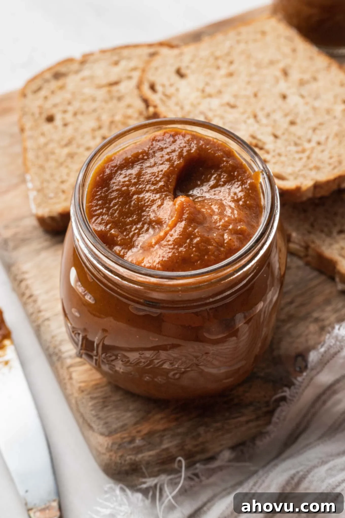 Autumn's Golden Spread 2 A beautifully styled jar of golden homemade pumpkin butter sits on a rustic wooden cutting board, flanked by two slices of artisanal bread, hinting at its delicious use as a spread.