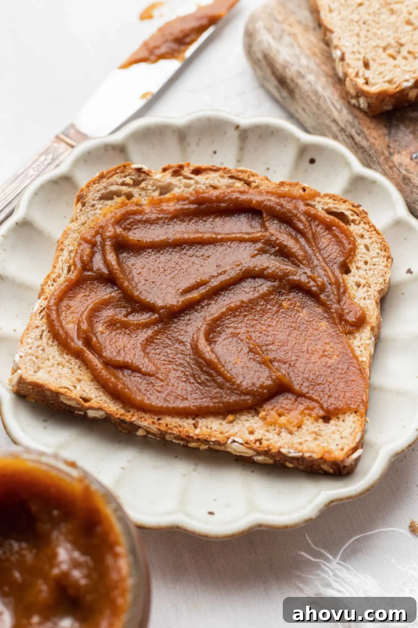 Autumn's Golden Spread 5 A perfectly toasted slice of artisanal bread, generously slathered with creamy, rich pumpkin butter, presented on a simple white plate ready to be enjoyed.