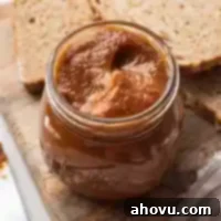 Autumn's Golden Spread 7 A jar filled with golden pumpkin butter, perfectly set on a rustic wooden cutting board, with slices of soft bread in the background.