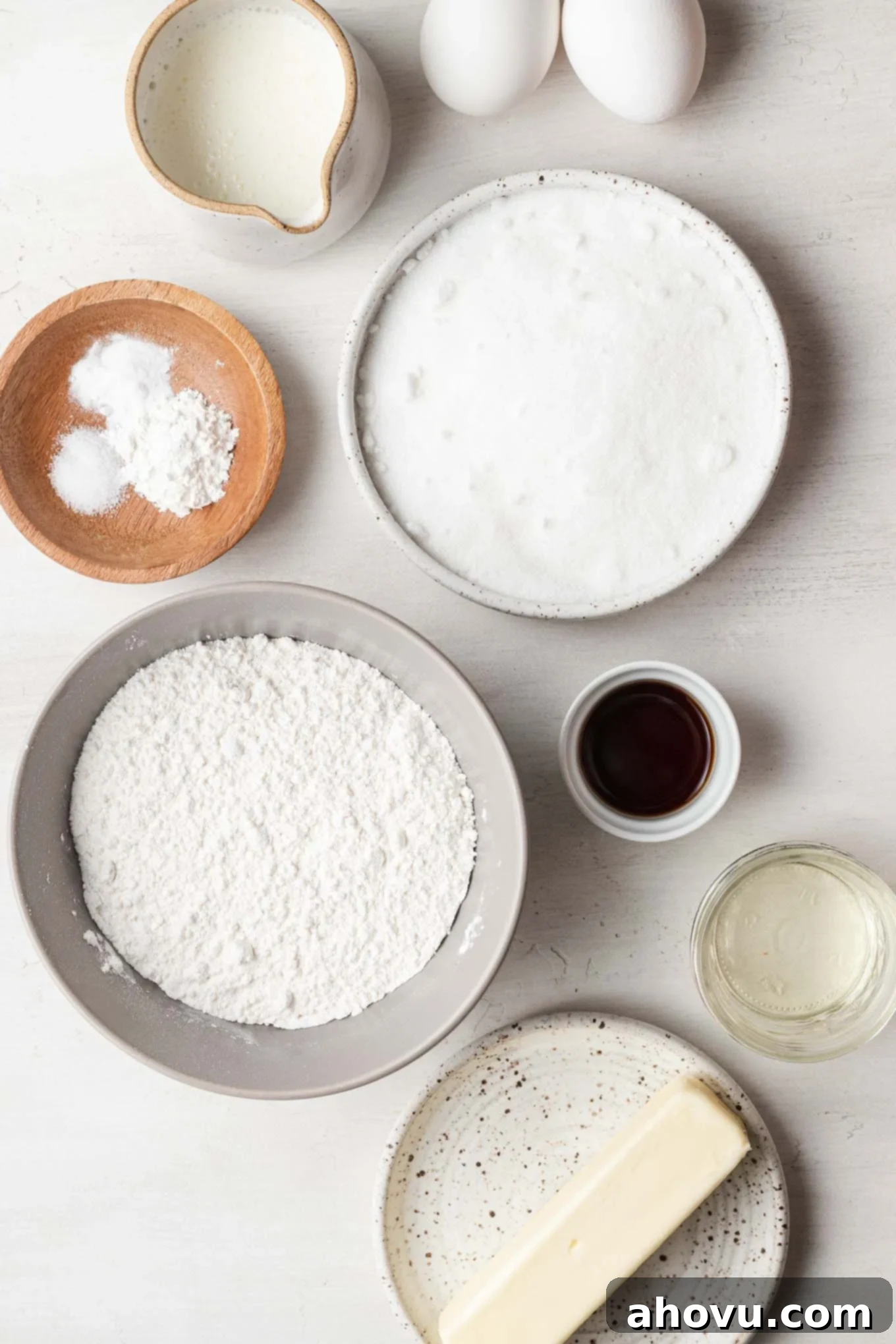 An overhead view showcasing all the essential ingredients neatly arranged for baking a small vanilla cake.