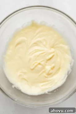 An overhead view of the wet ingredients for a vanilla cake in a glass mixing bowl, perfectly blended.