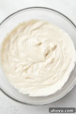 An overhead view of luscious vanilla cake batter in a glass mixing bowl, ready for baking.