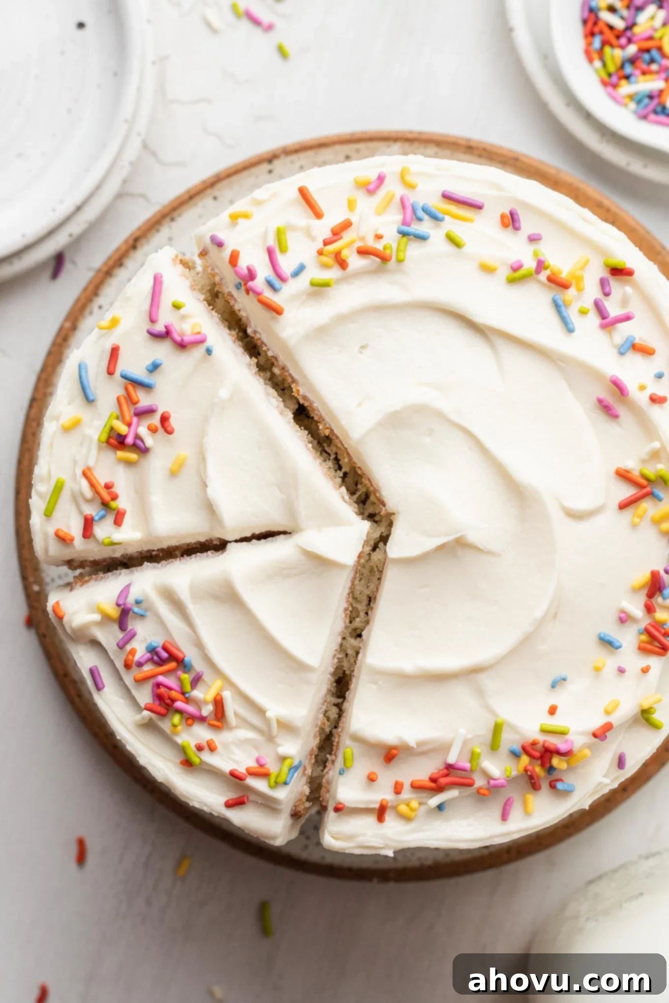An overhead view of a beautifully frosted 6-inch vanilla cake with two perfect slices already removed, revealing the moist layers.