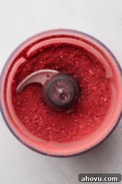 Freeze-dried strawberries transformed into a fine, vibrant pink powder in a food processor, ready for mixing.